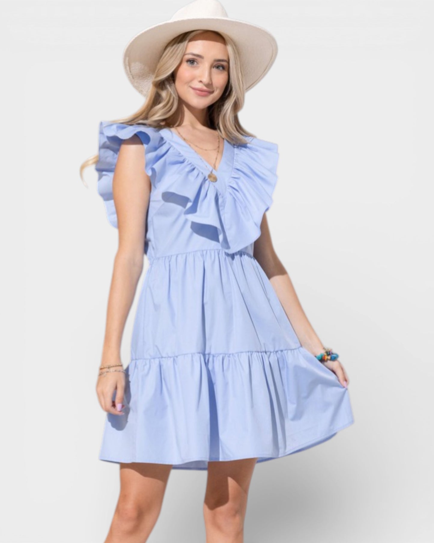 Woman wearing a light blue dress with ruffled sleeves and a hat on a white background
