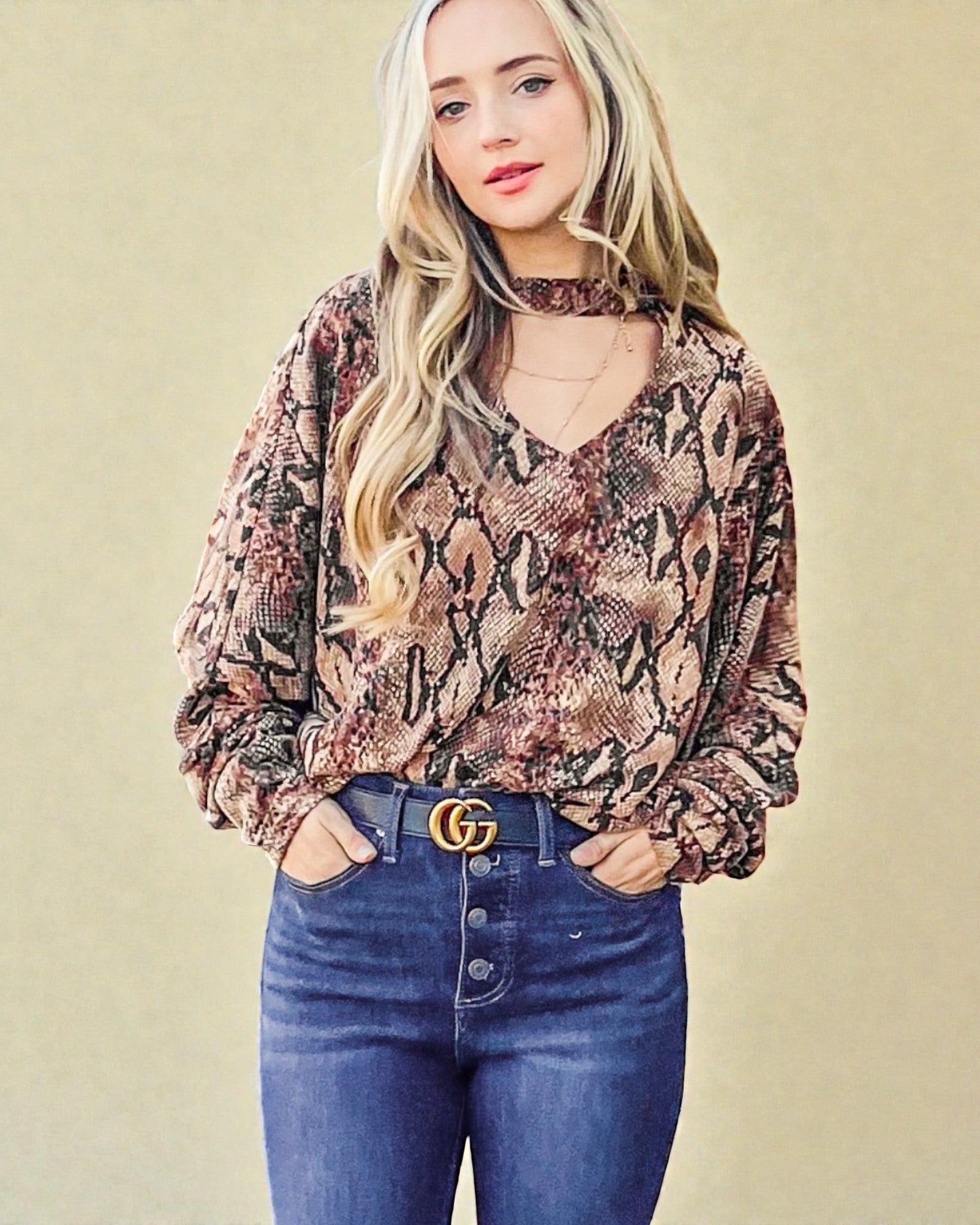 Woman wearing a patterned blouse and blue jeans with a beige background
