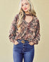 Woman wearing a patterned blouse and blue jeans with a beige background