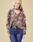 Woman wearing a patterned blouse and blue jeans with a beige background