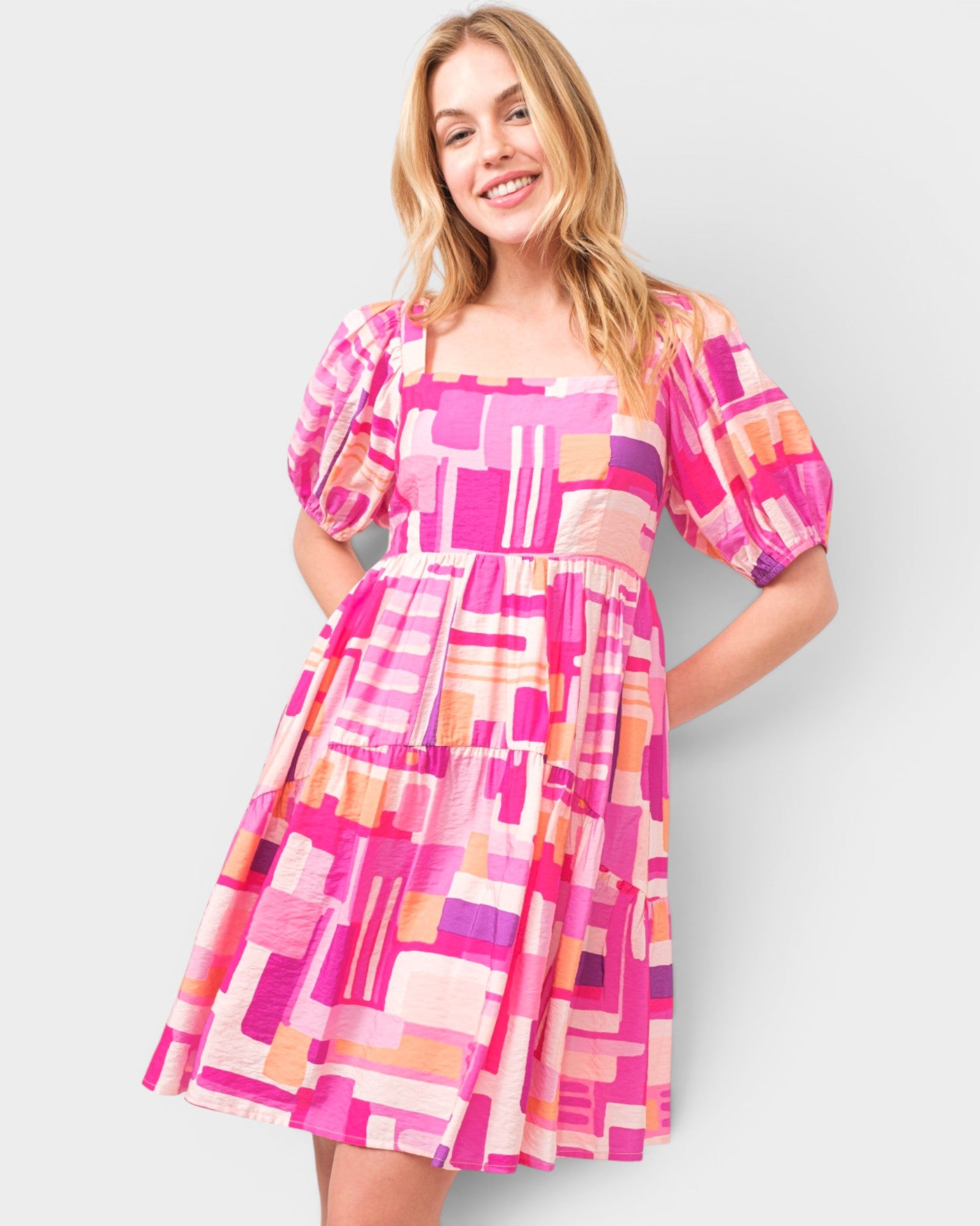 Woman wearing a colorful geometric pattern dress on a plain background