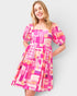 Woman wearing a colorful geometric pattern dress on a plain background