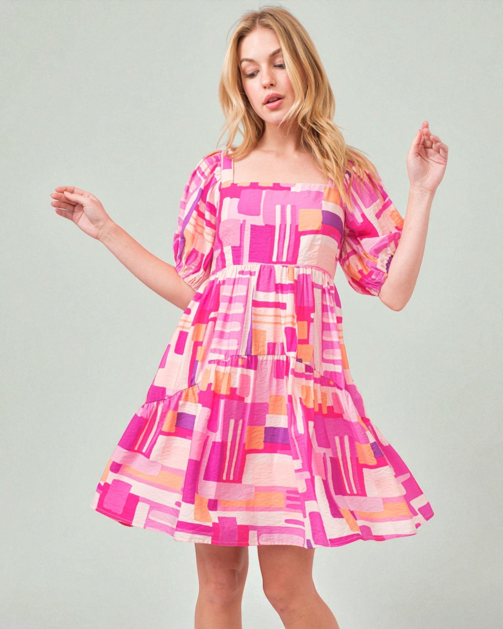 Woman wearing a colorful geometric patterned dress on a plain background