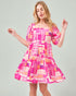 Woman wearing a colorful geometric patterned dress on a plain background