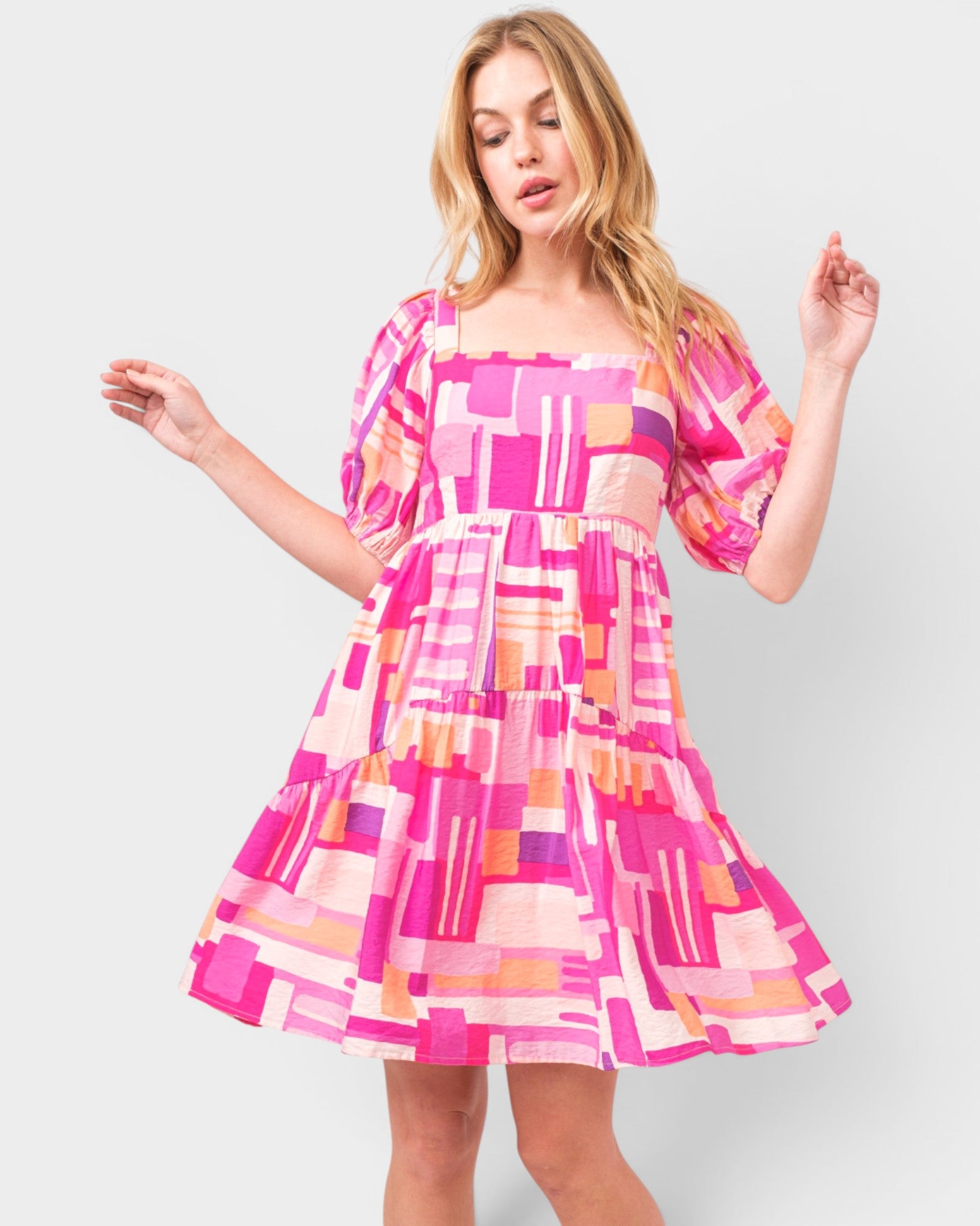 Woman wearing a colorful geometric patterned dress on a light gray background