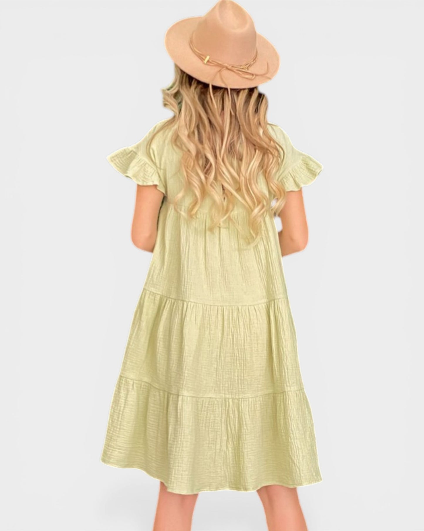 Woman wearing a light green dress and beige hat on a white background