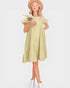 Woman wearing a light green dress with ruffled sleeves and white boots on a white background