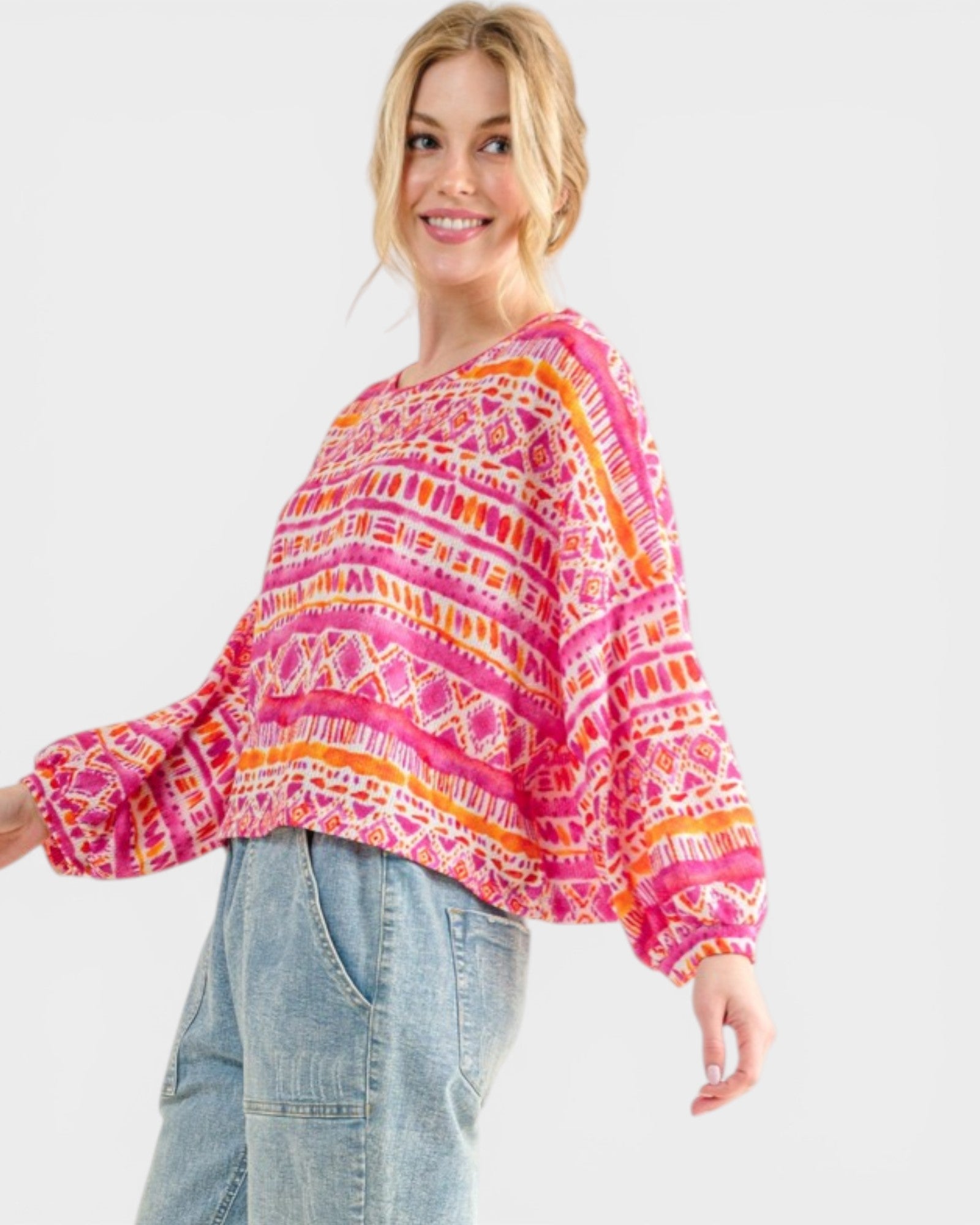 Woman wearing a colorful patterned sweater and jeans on a white background