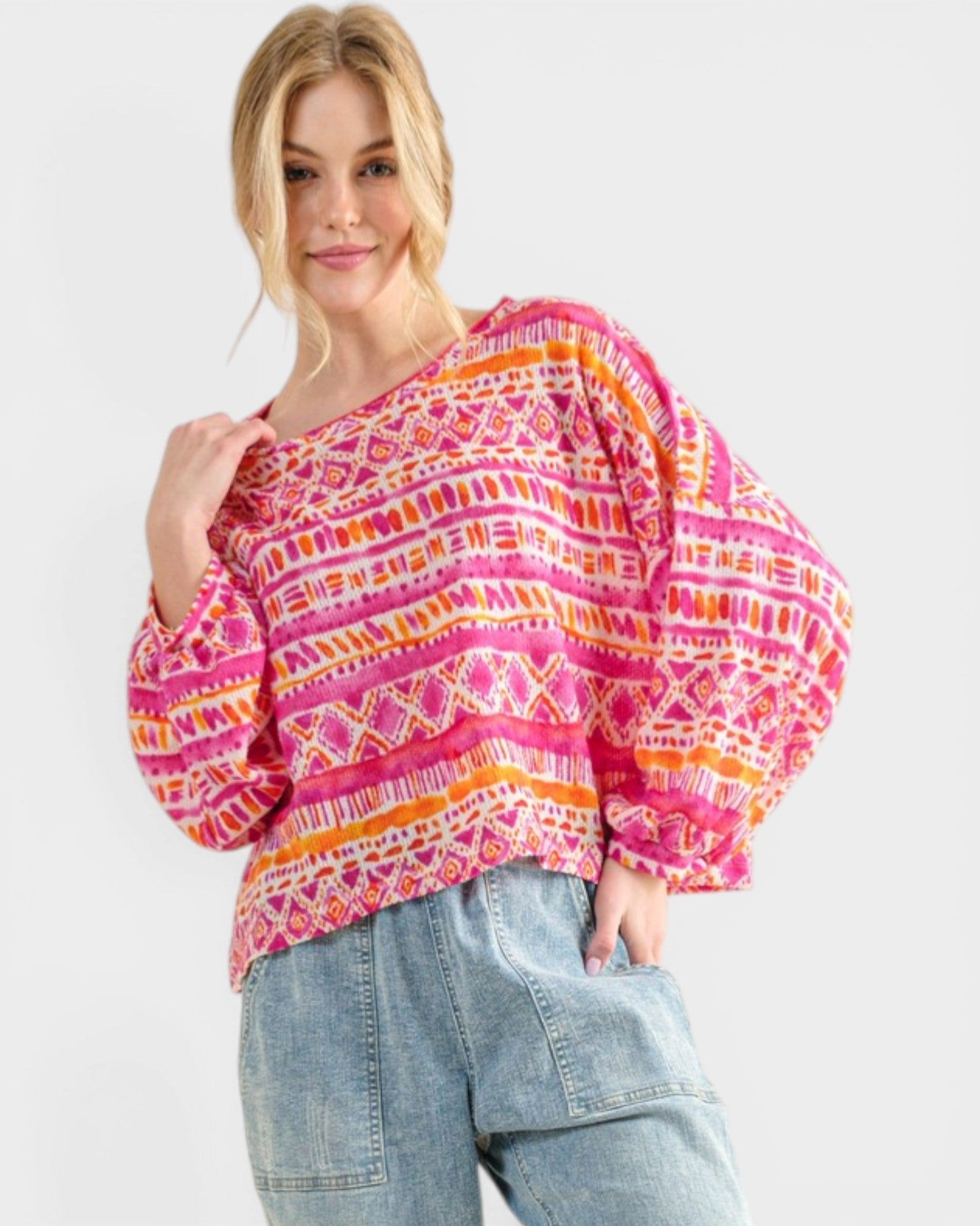 Woman wearing a colorful patterned top and jeans on a white background