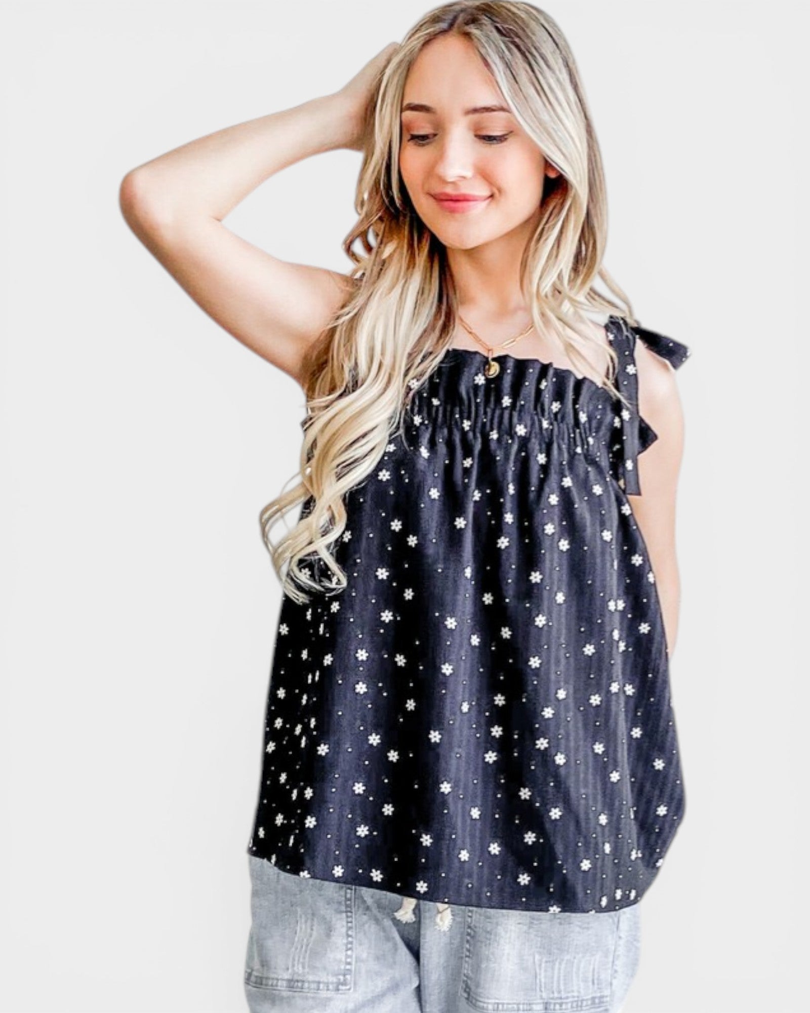 Woman wearing a navy blue top with white star pattern on a plain background