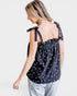Woman wearing a black polka dot top with thin straps on a white background