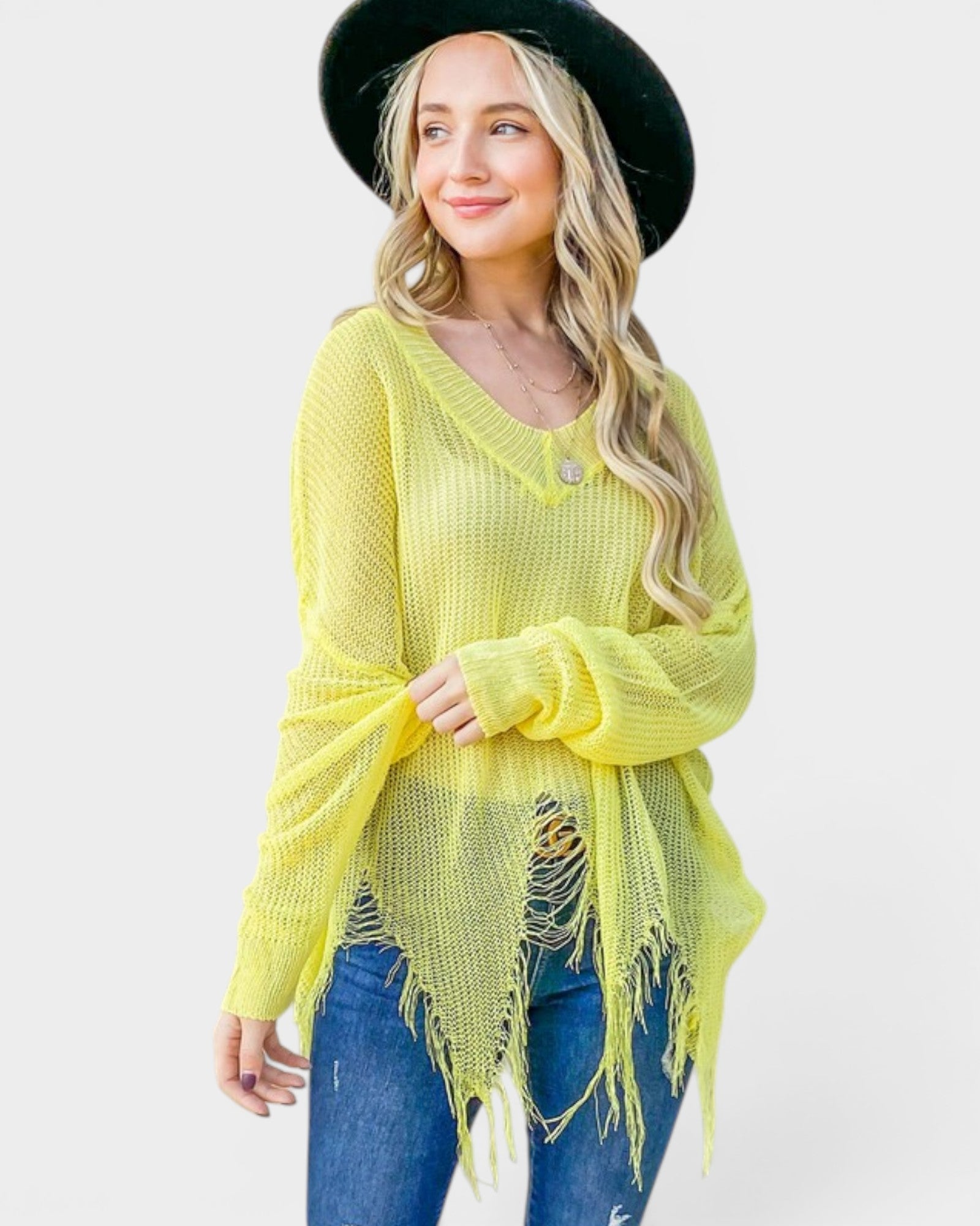 Woman wearing a bright yellow sweater with frayed edges and a black hat on a white background