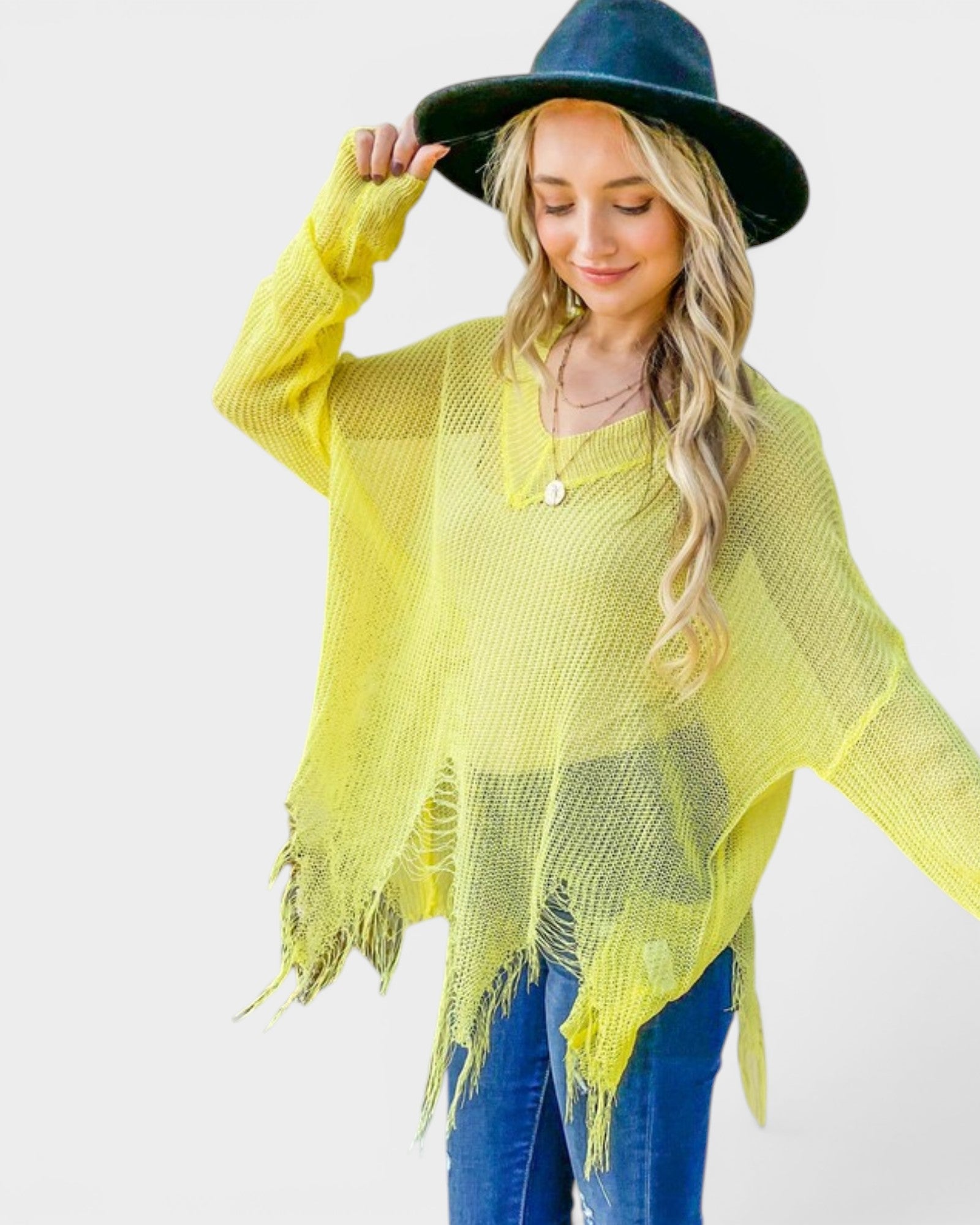 Woman wearing a yellow fringe poncho and blue hat on a white background