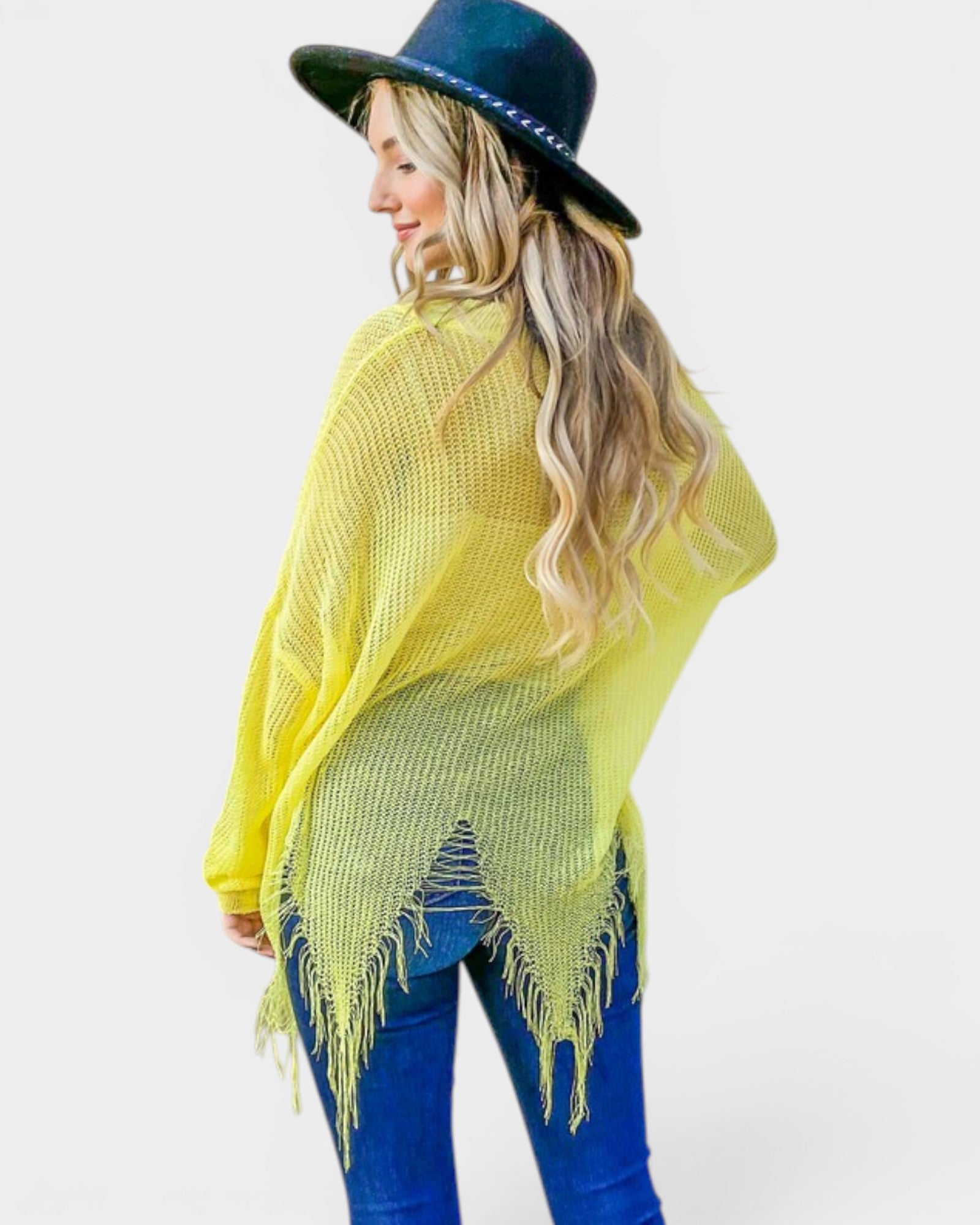 Woman wearing a bright yellow poncho and blue jeans with a white background