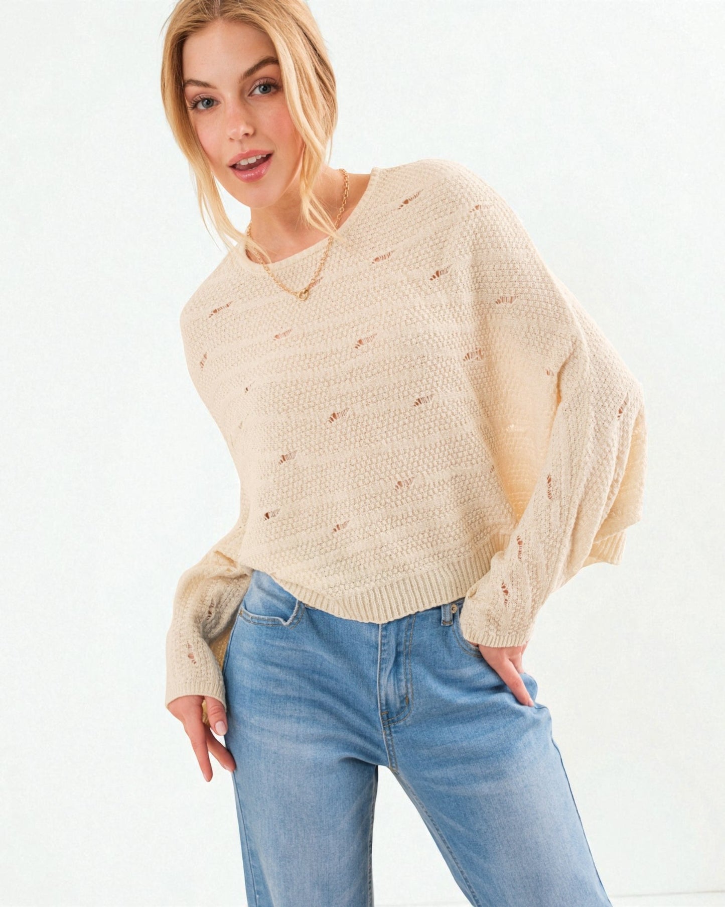 Woman wearing a beige sweater and blue jeans on a white background