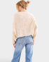 Person wearing a beige sweater and blue jeans on a white background