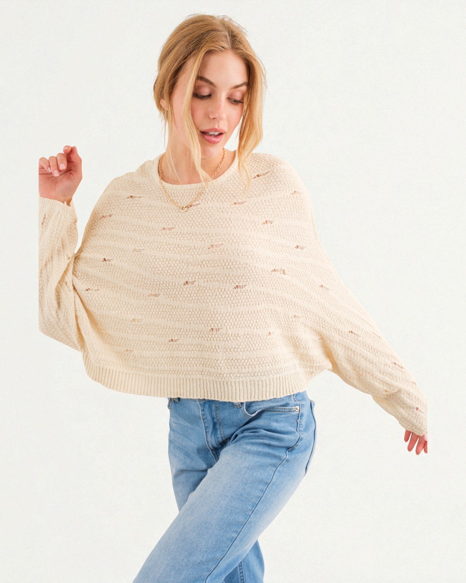 Woman wearing a beige sweater and blue jeans on a white background