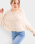 Woman wearing a beige sweater and blue jeans on a light gray background