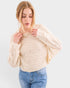 Woman wearing a beige sweater and blue jeans on a white background