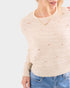 Beige sweater with subtle pattern worn by a person on a light gray background