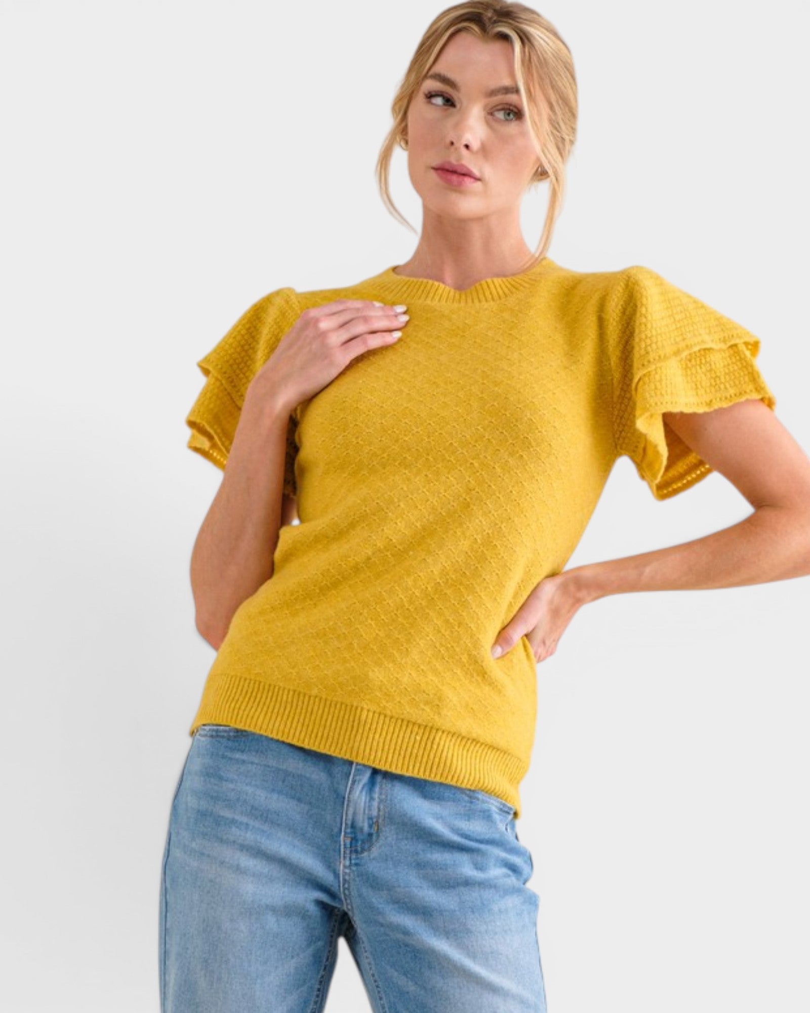 Woman wearing a yellow sweater with ruffled sleeves on a white background