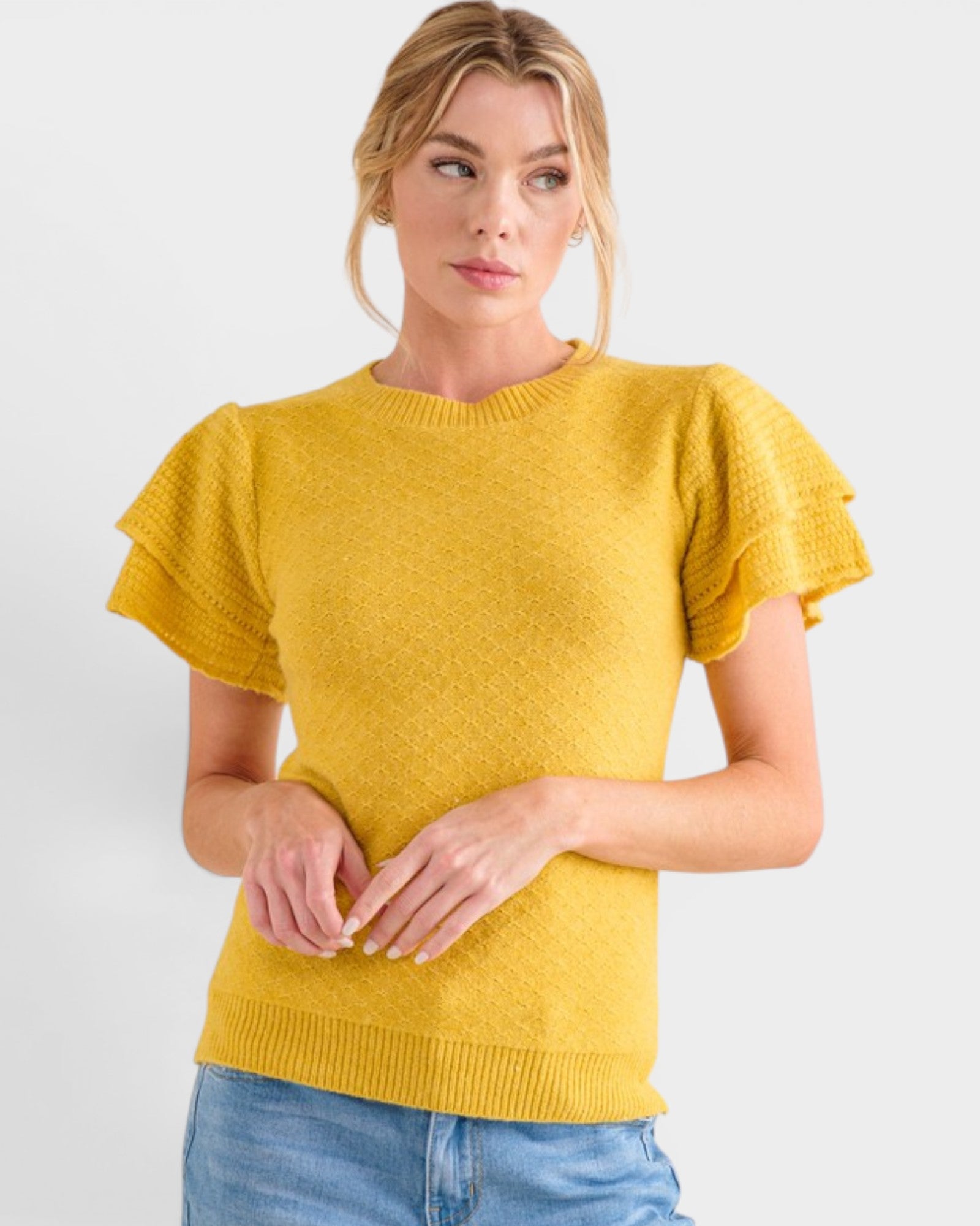 Woman wearing a yellow knit sweater against a white background
