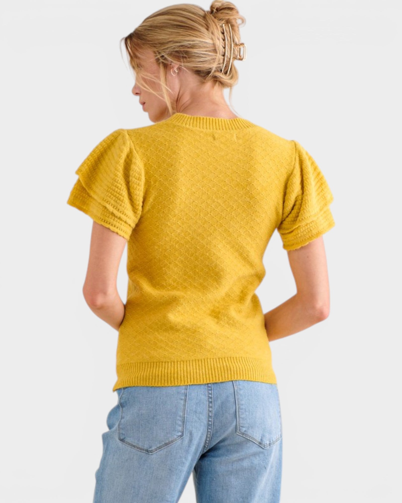 Person wearing a yellow sweater and blue jeans on a white background