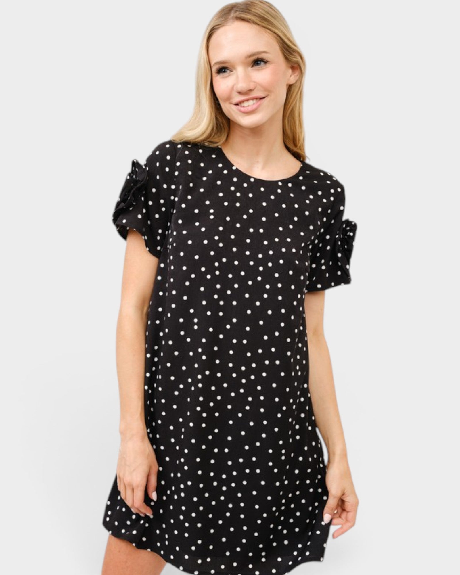 Woman wearing a black dress with white polka dots on a white background