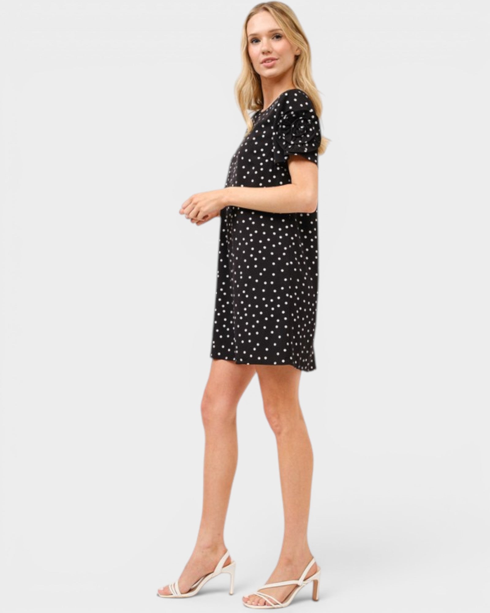 Woman wearing a black dress with white polka dots on a white background