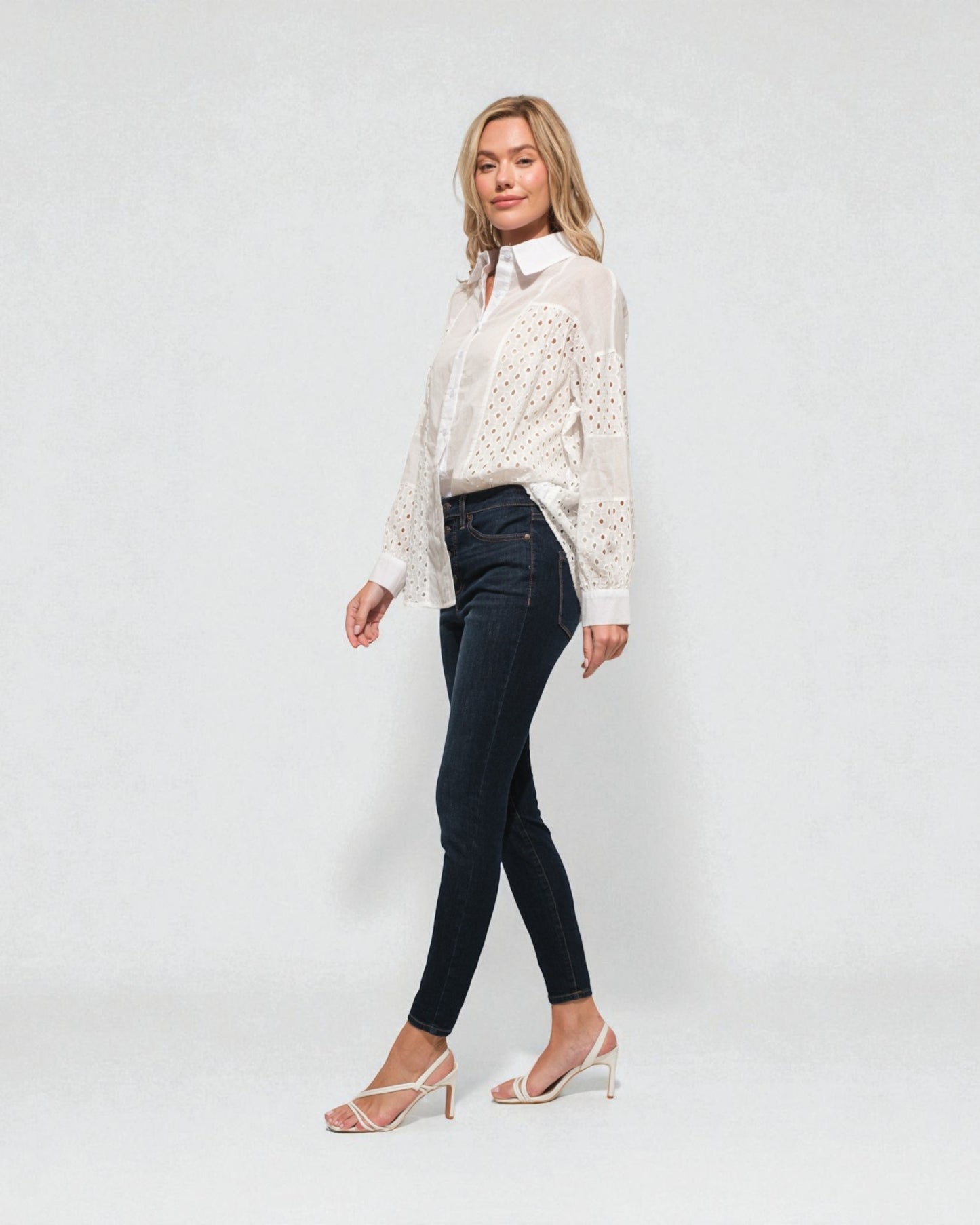 Woman wearing a white blouse and black pants on a plain background