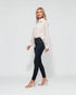 Woman wearing a white blouse and black pants on a plain background