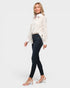 Woman wearing a white blouse with black polka dots and dark jeans on a white background