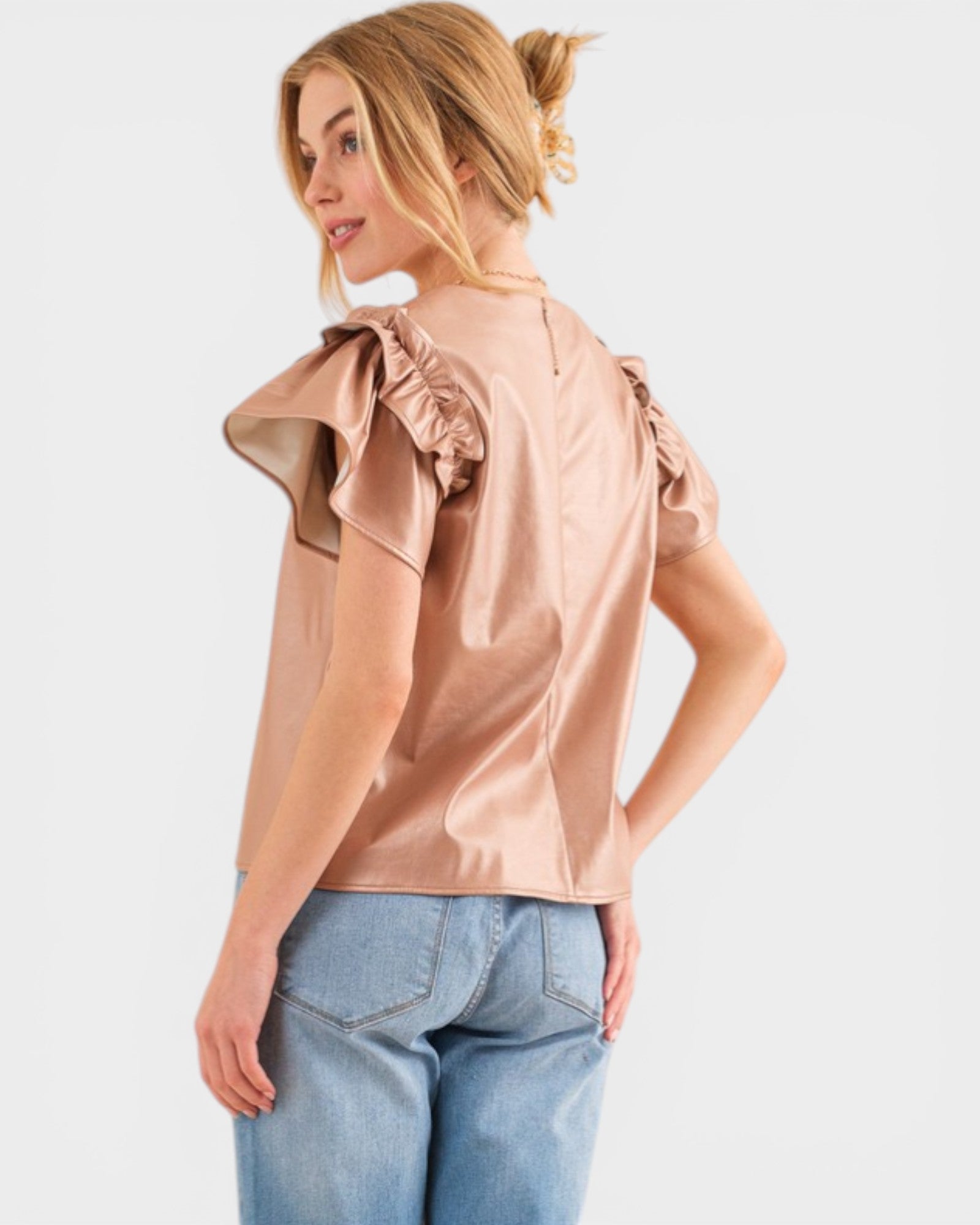 Woman wearing a light pink blouse with ruffled shoulders on a white background