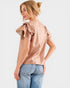Woman wearing a light pink blouse with ruffled shoulders on a white background