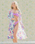 Woman wearing a floral cover-up and purple bikini against a patterned background
