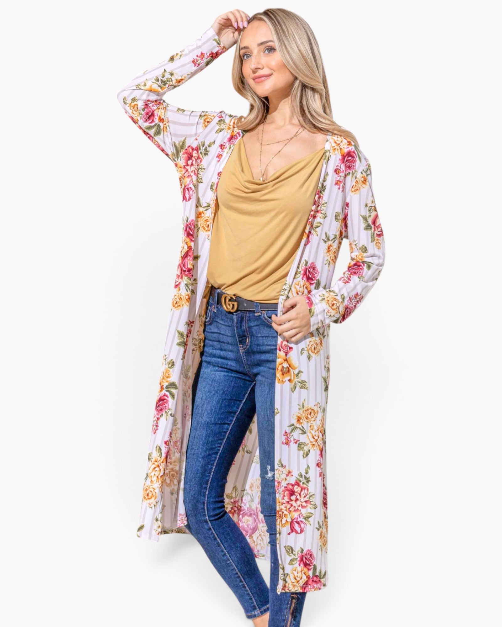 A woman modeling a long-sleeve, open-front floral kimono cardigan over a mustard yellow top and blue jeans, photographed against a plain light gray studio background.