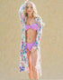 Woman wearing a floral cover-up and purple bikini against a beige background