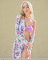 Woman wearing a floral robe over a purple bikini against a beige background