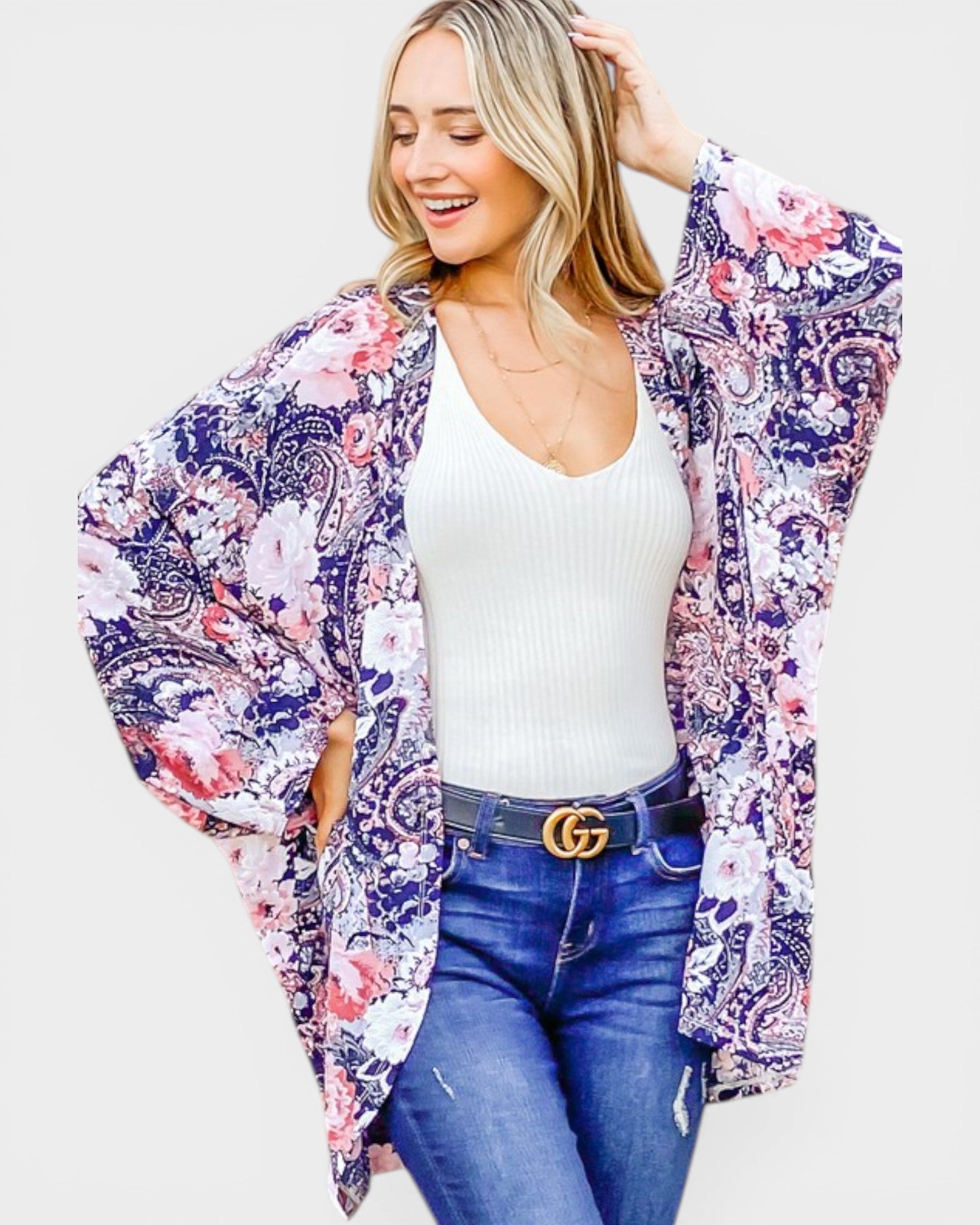 Woman wearing a floral kimono over a white top and blue jeans on a white background