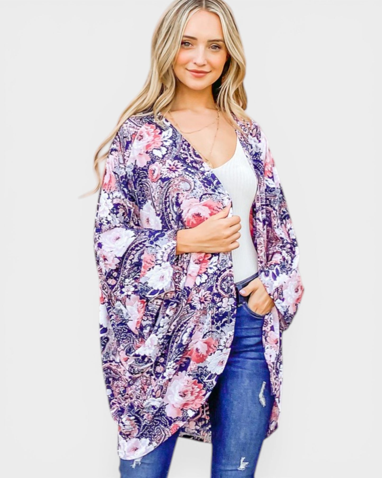 Woman wearing a floral kimono over a white top and blue jeans on a white background
