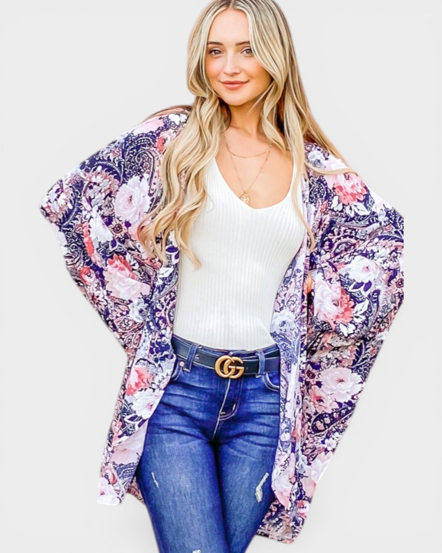 Woman wearing a floral kimono over a white top and blue jeans on a white background