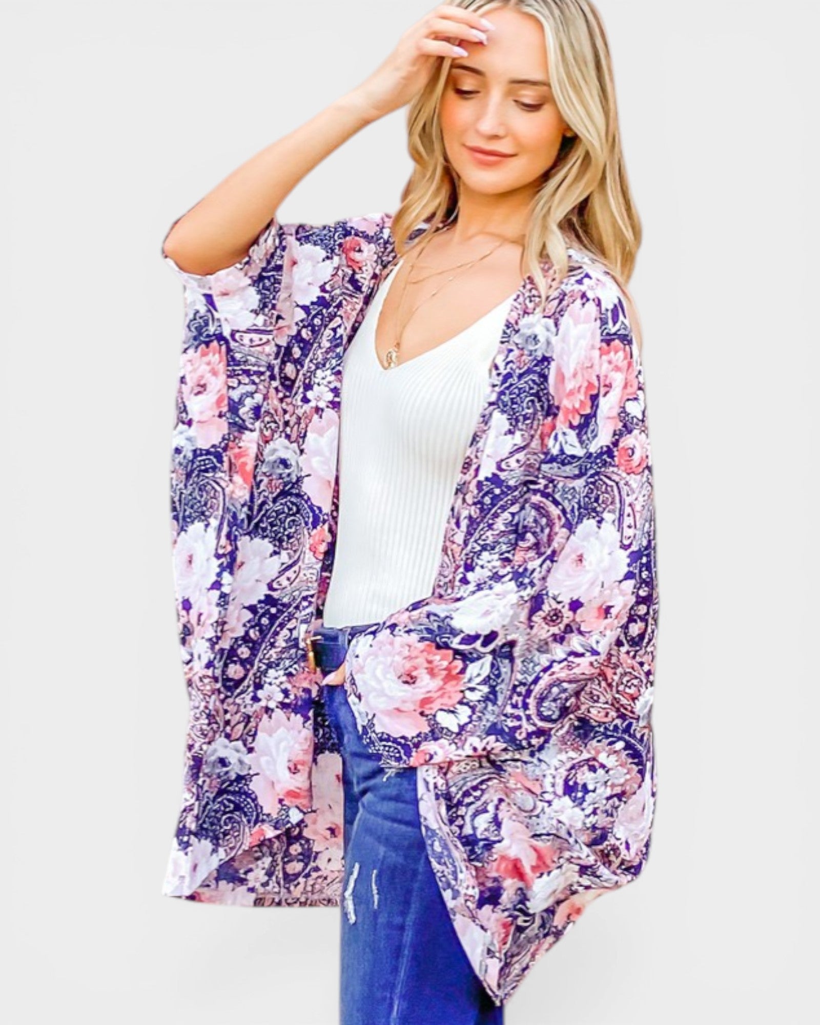 Woman wearing a floral kimono over a white top and blue jeans on a white background