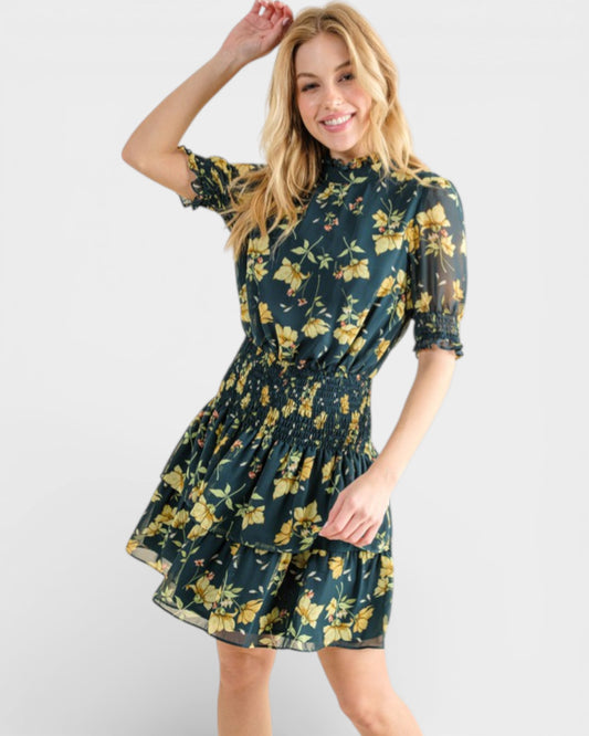 Woman wearing a floral dress with yellow flowers on a plain background