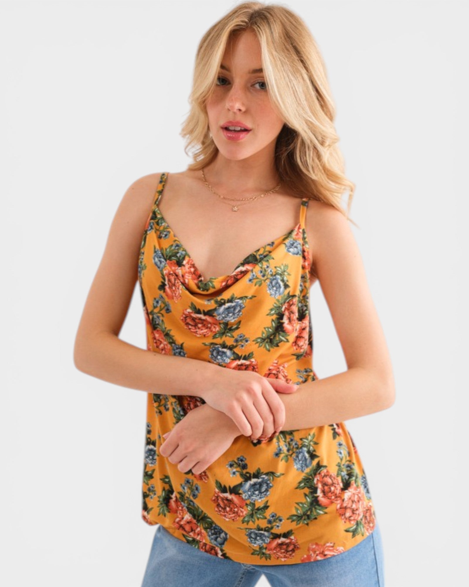 Woman wearing a mustard yellow floral tank top against a white background