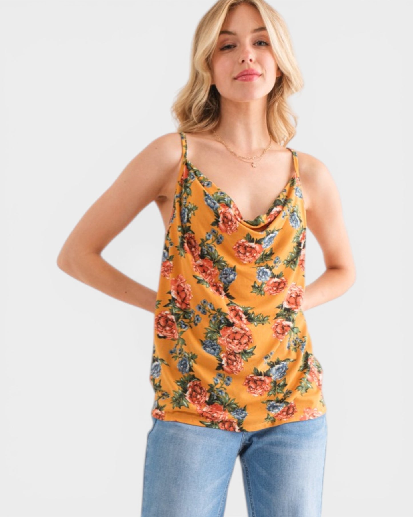 Woman wearing a yellow floral tank top and blue jeans on a white background
