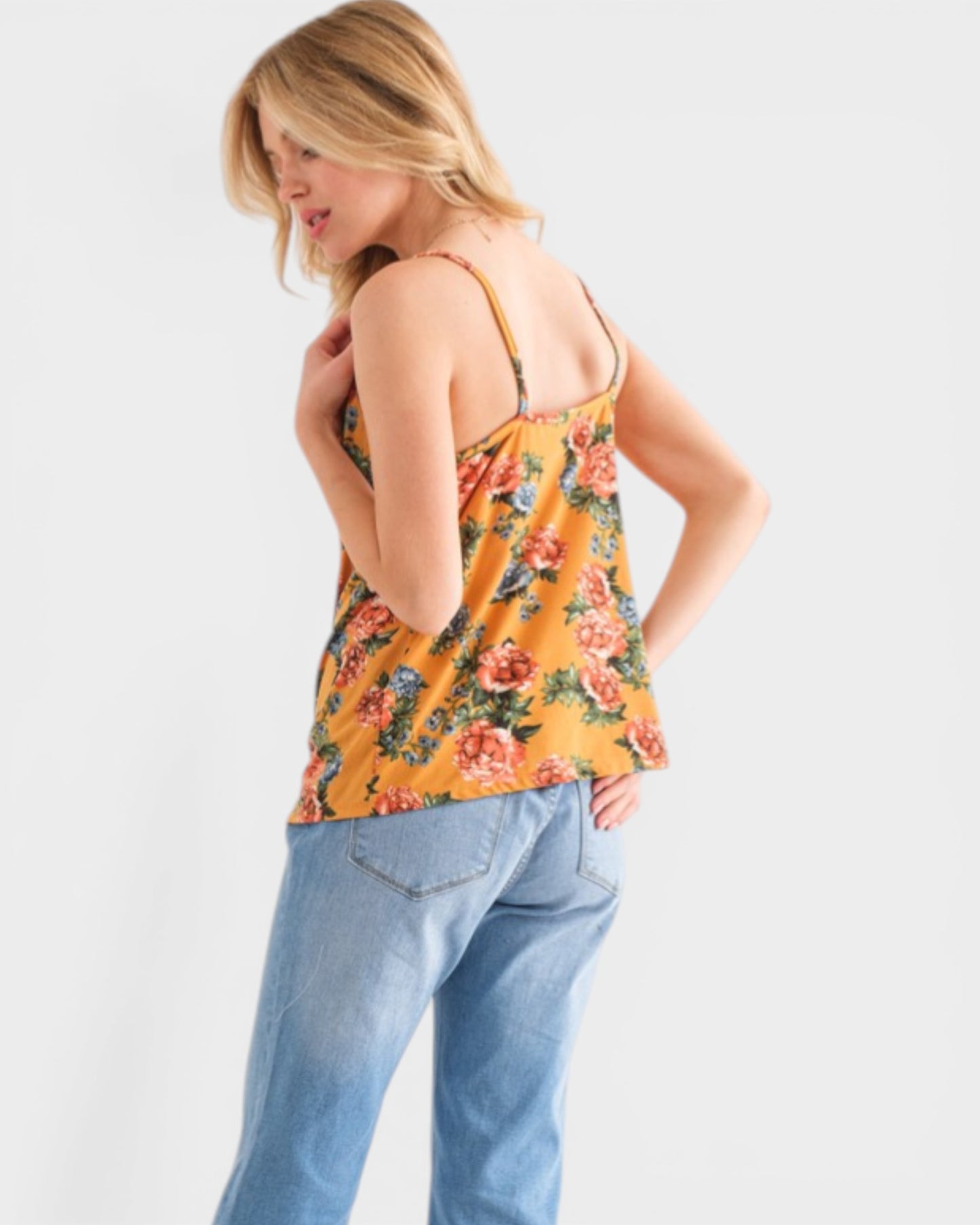 Woman wearing a floral tank top and jeans on a white background