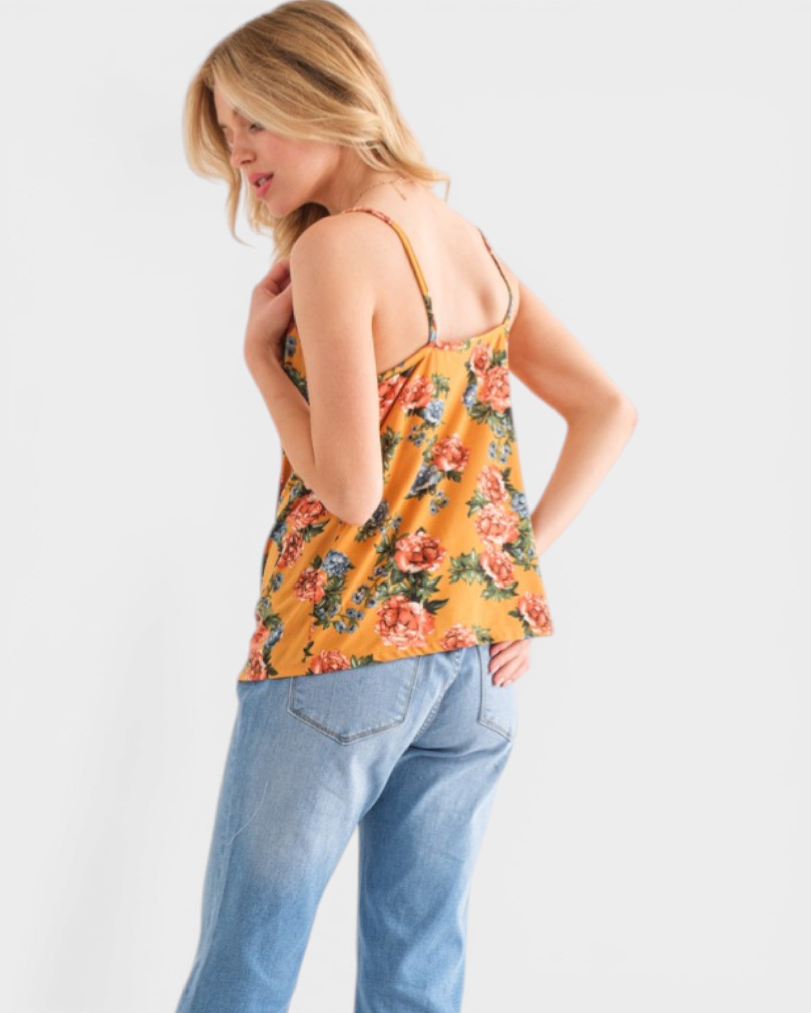 Woman wearing a floral tank top and jeans on a white background