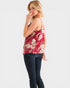 Woman wearing a red floral top and dark jeans on a white background