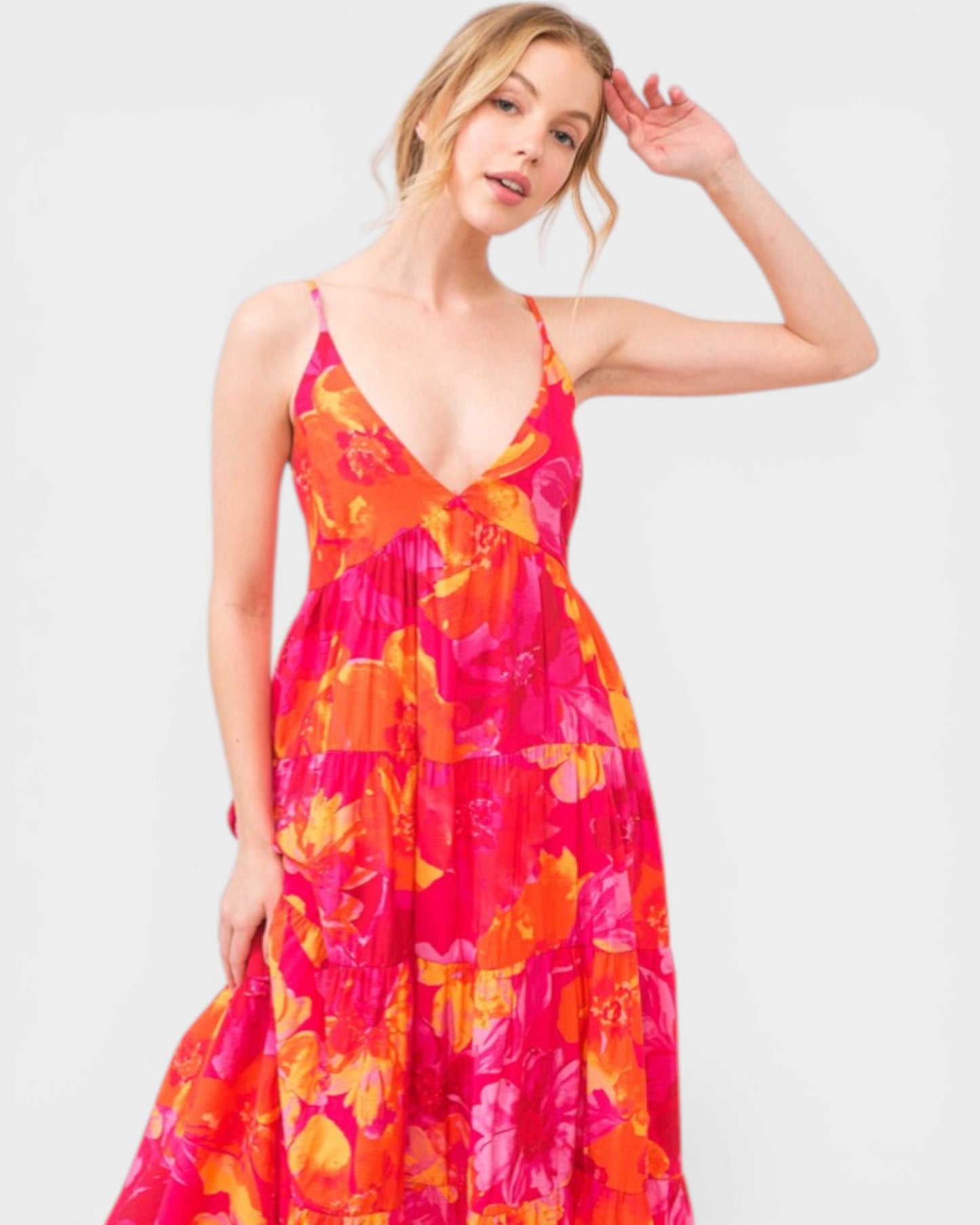 Woman wearing a vibrant floral dress on a plain background