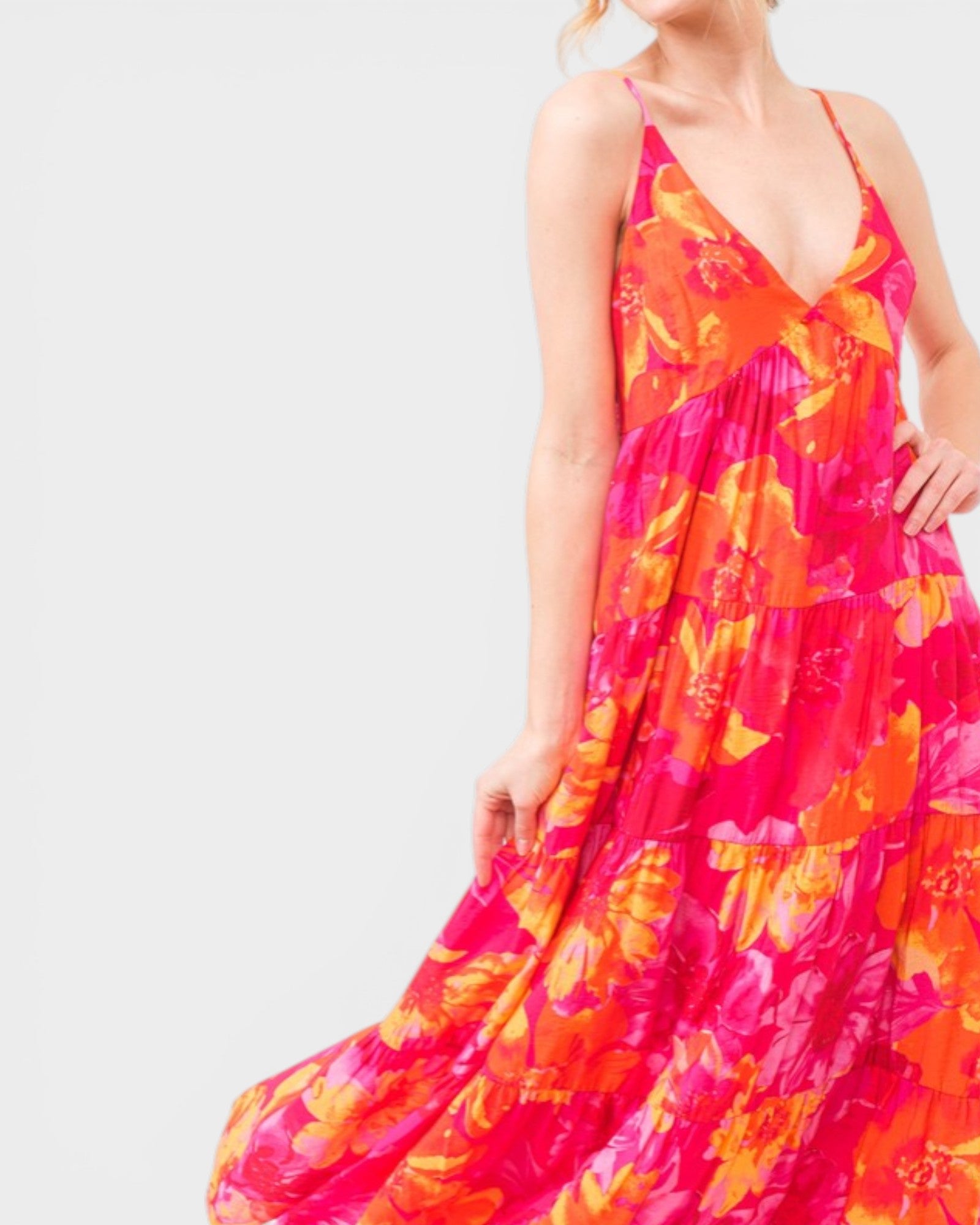 Woman wearing a vibrant floral dress on a plain background